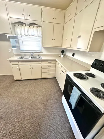 a kitchen with stainless steel appliances a stove a sink and white cabinets