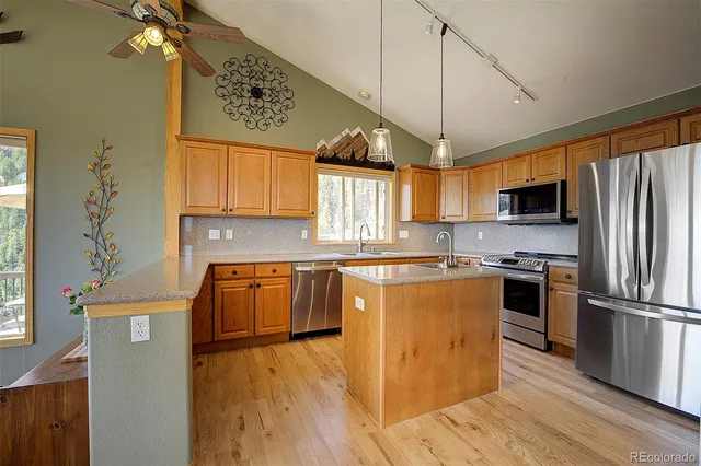 a kitchen with stainless steel appliances granite countertop a refrigerator a sink dishwasher a stove and a dining table with wooden floor