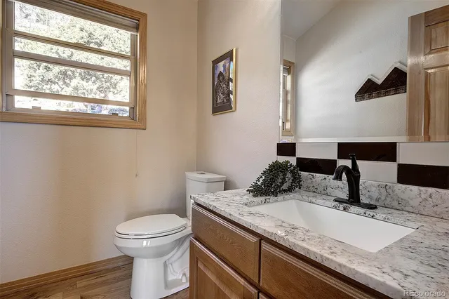 a bathroom with a granite countertop toilet sink and mirror