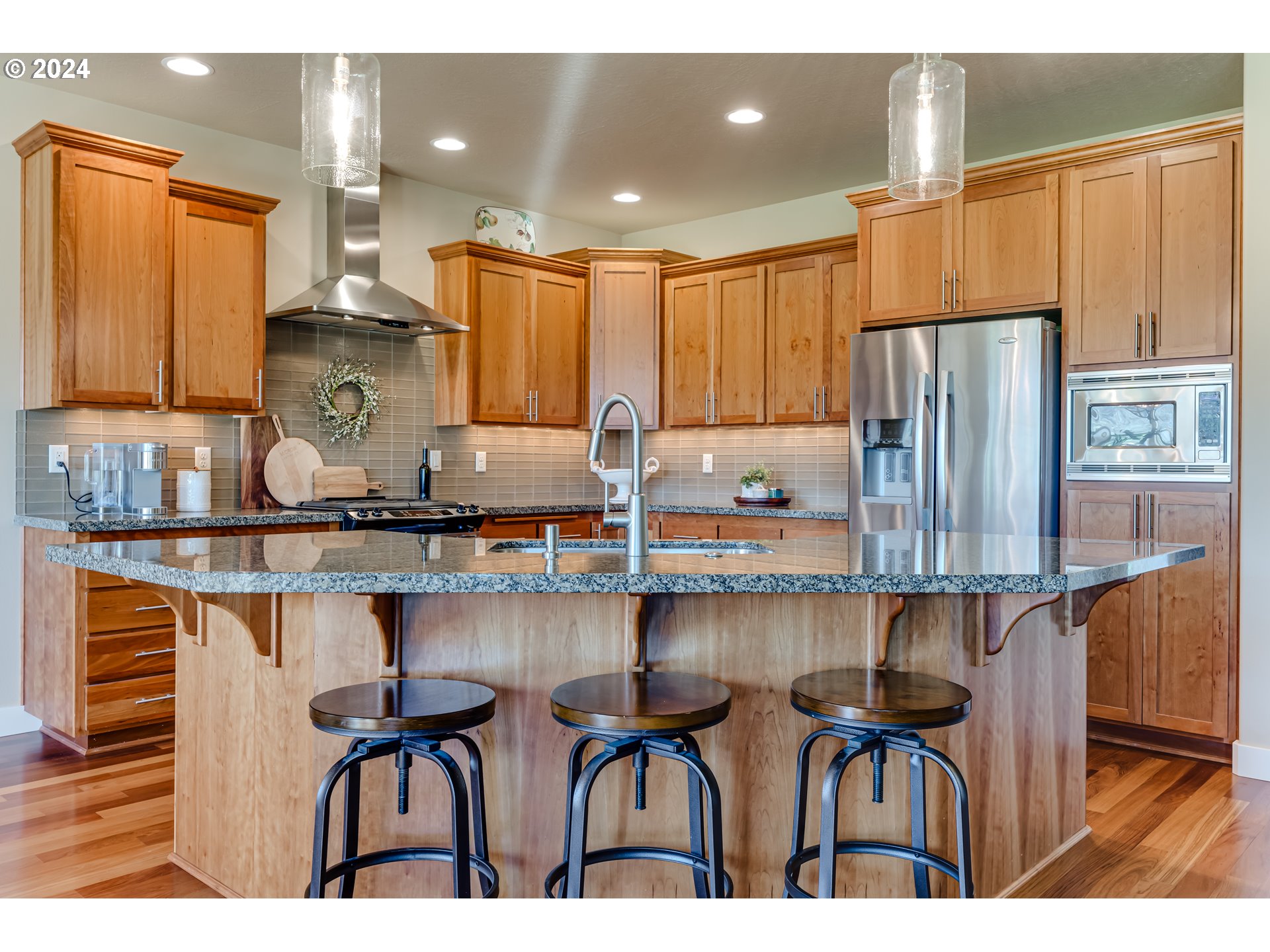 6234 Graystone Loop Springfield, OR 97478 - Photo 20 of 43 a kitchen with stainless steel appliances granite countertop a table chairs in it and wooden floors