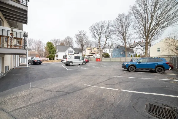 a view of road with card parked on side and retail shops
