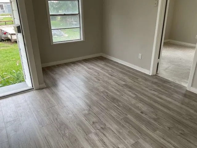 an empty room with wooden floor and windows