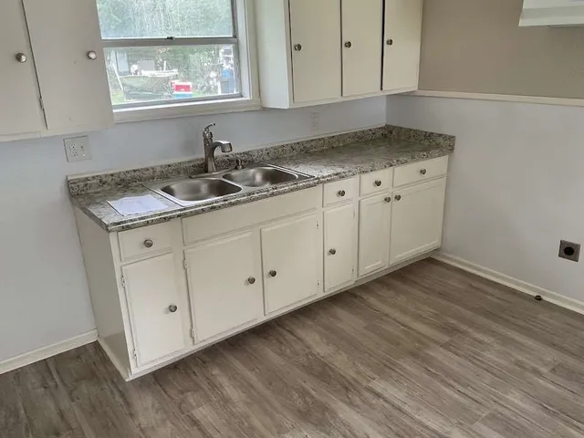 a kitchen with granite countertop white cabinets and a wooden floor