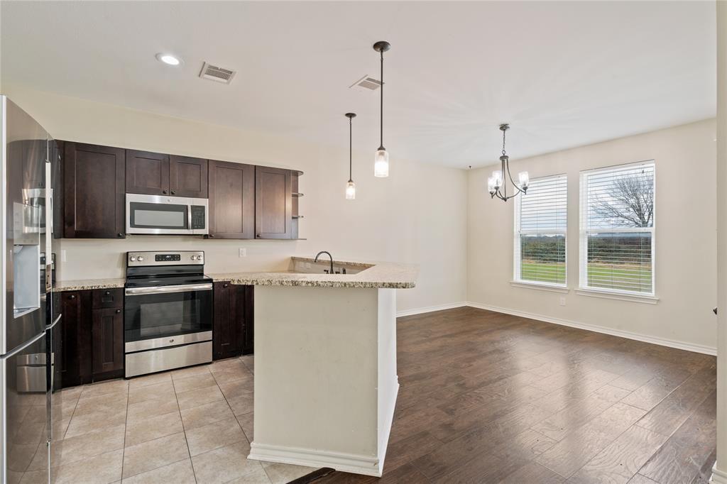 104 Eagle Meadow Drive Weatherford, TX 76087 - Photo 15 of 40 a kitchen with stainless steel appliances granite countertop a stove a sink and a refrigerator