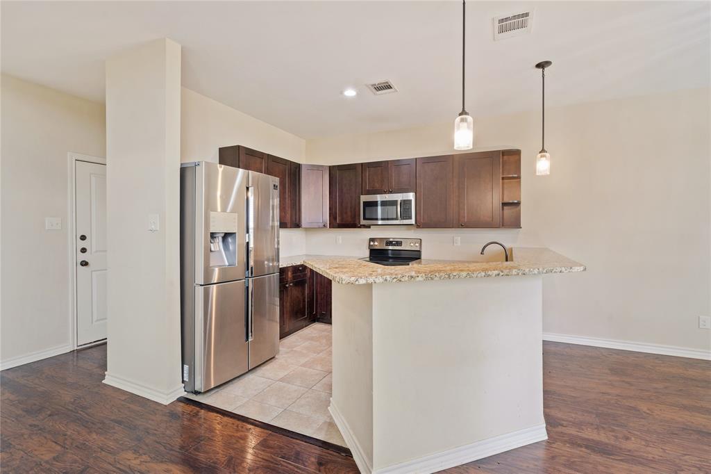104 Eagle Meadow Drive Weatherford, TX 76087 - Photo 10 of 40 a kitchen with kitchen island a refrigerator a stove a sink and a oven with wooden floor