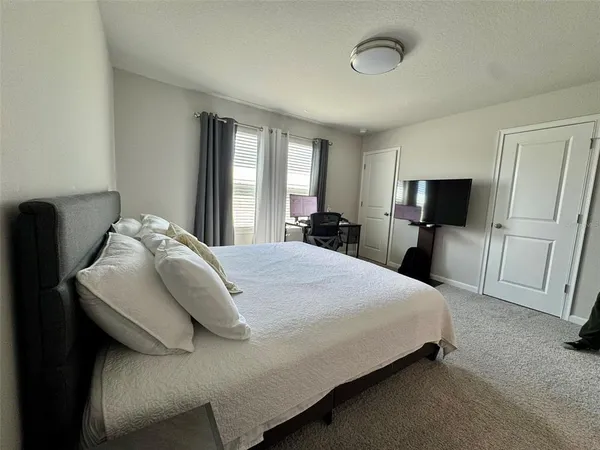 a spacious bedroom with a bed and a flat tv screen