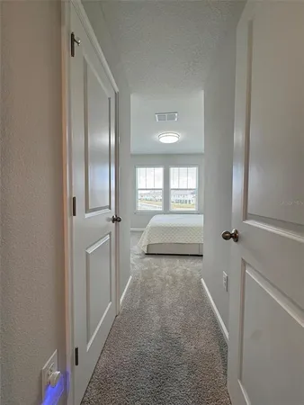 a view of a hallway to a livingroom with wooden floor and window