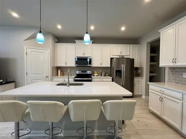 a kitchen with stainless steel appliances a dining table chairs refrigerator and microwave