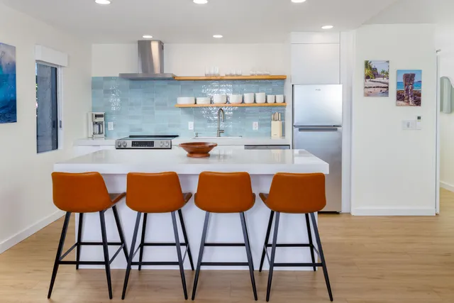a kitchen with stainless steel appliances granite countertop a table chairs and a refrigerator