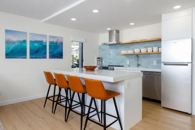 a kitchen with stainless steel appliances kitchen island a table chairs in it and wooden floors