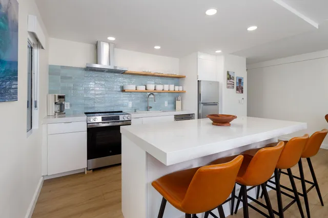 a kitchen with stainless steel appliances a table chairs in it and wooden floors