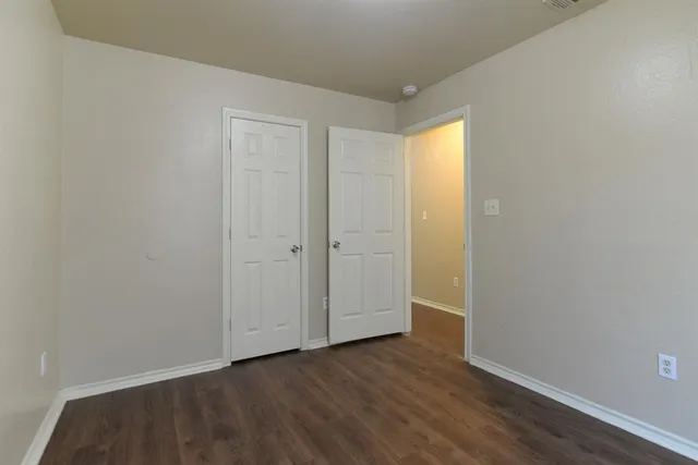 a view of an empty room with wooden floor and closet