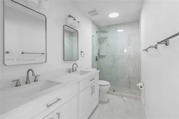 a bathroom with a double vanity sink toilet mirror and shower