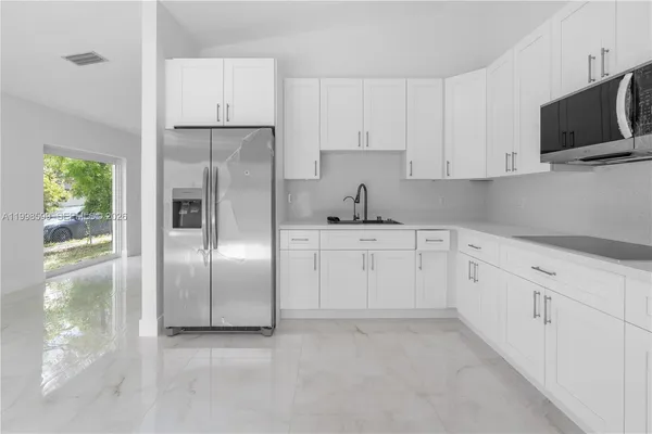 a kitchen with white cabinets and refrigerator