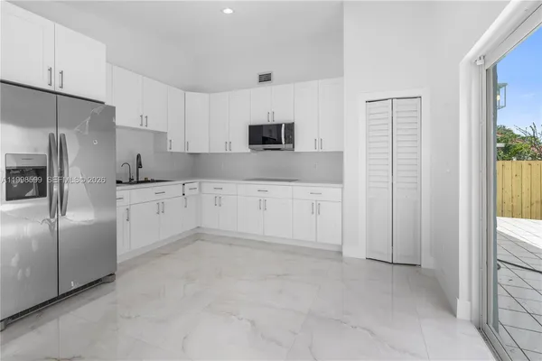 a kitchen with white cabinets and refrigerator