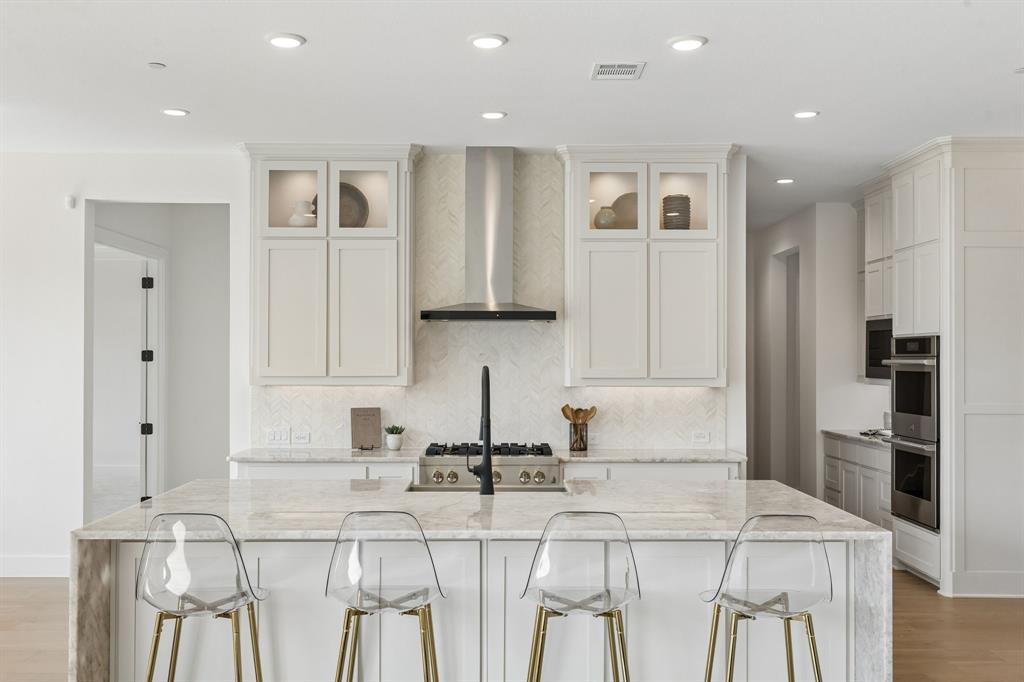 460 Harrison Lane Prosper, TX 75078 - Photo 9 of 40 Spacious kitchen featuring a large island, stainless steel appliances, recessed lighting, and ample white cabinetry with glass-front accents