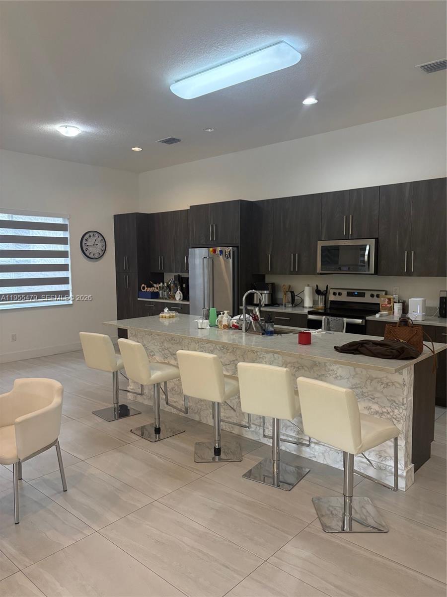 15062 Southwest 177th Terrace Miami, FL 33187 - Photo 15 of 41 a kitchen with stainless steel appliances a stove a sink a microwave a refrigerator and chairs