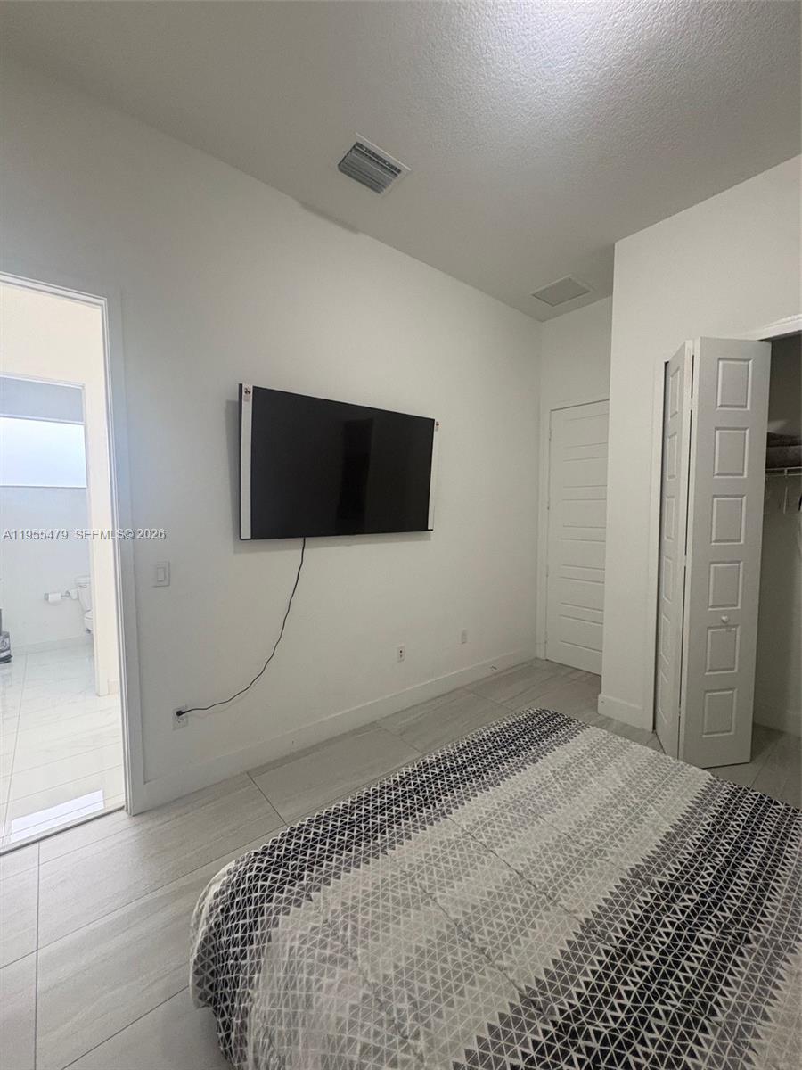 15062 Southwest 177th Terrace Miami, FL 33187 - Photo 31 of 41 a bedroom with a bed and a flat screen tv
