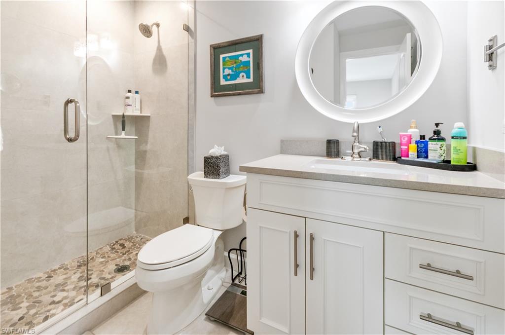 3150 Binnacle Drive, Unit 209 2J Naples, FL 34103 - Photo 15 of 32 a bathroom with a toilet sink vanity and mirror