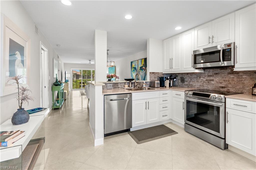 3150 Binnacle Drive, Unit 209 2J Naples, FL 34103 - Photo 2 of 32 a kitchen with white cabinets and appliances