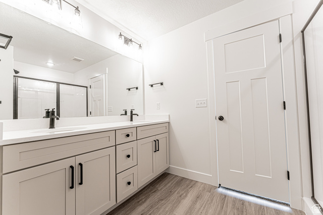 4774 Alder Drive Mapleton, UT 84664 - Photo 10 of 27 Full bathroom with double vanity, a shower stall, light wood-type flooring, and a textured ceiling