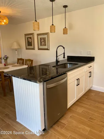 a kitchen with stainless steel appliances granite countertop a sink a stove and a wooden floors