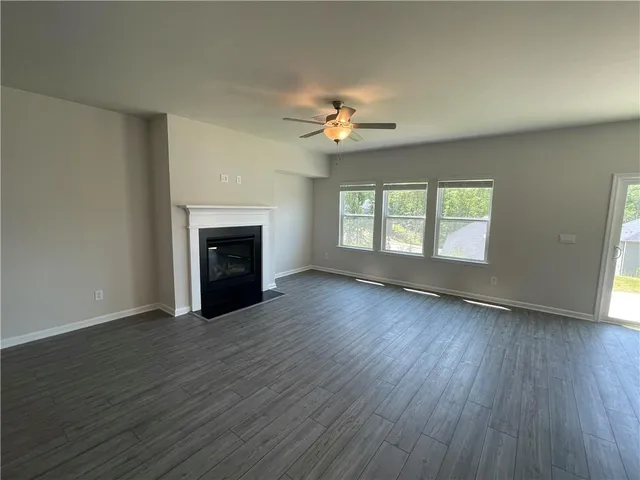 an empty room with wooden floor fireplace and windows