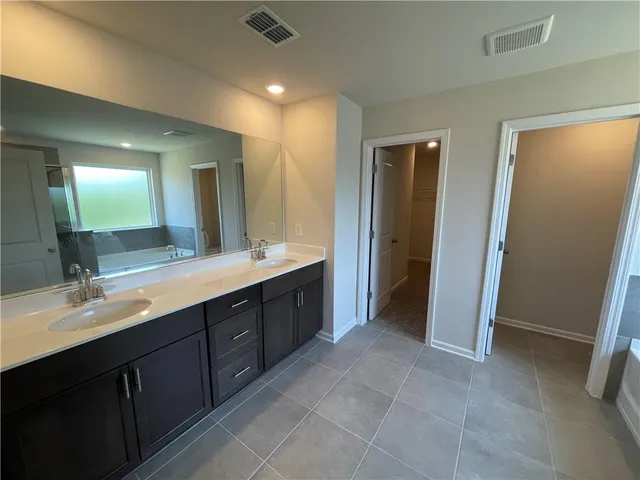 a spacious bathroom with a double vanity sink a large mirror and a shower