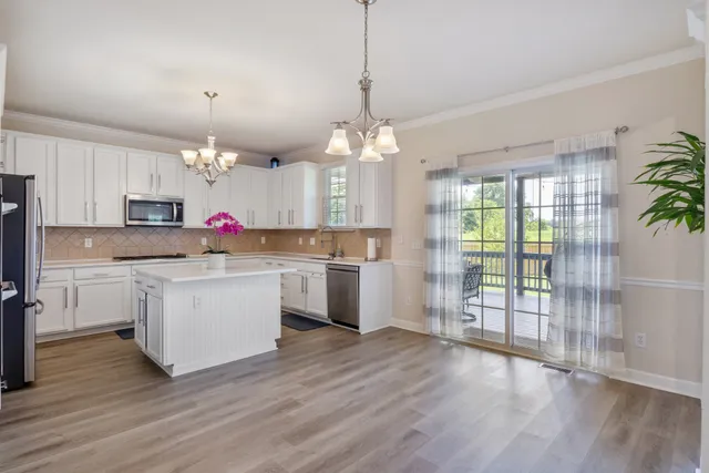 a kitchen with stove and white cabinets with wooden floor