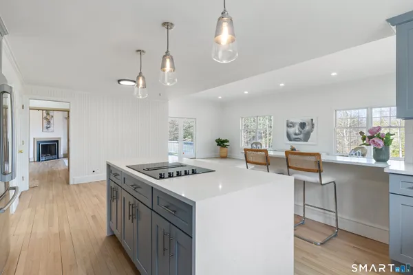 a kitchen with stainless steel appliances a stove a sink a dining table and chairs with wooden floor