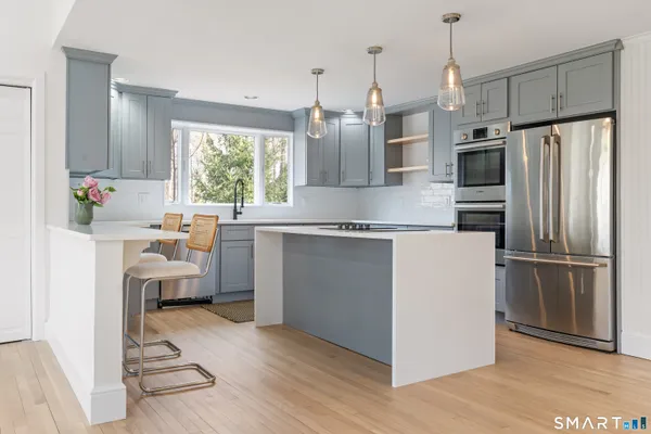 a kitchen with a refrigerator a sink dishwasher a stove and a window