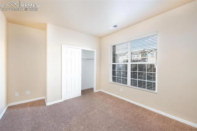 an empty room with windows fireplace and ceiling fan