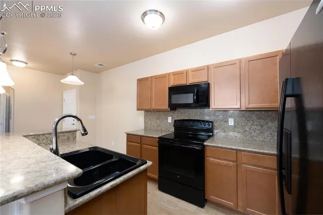 a kitchen with stainless steel appliances granite countertop a sink a stove and a refrigerator