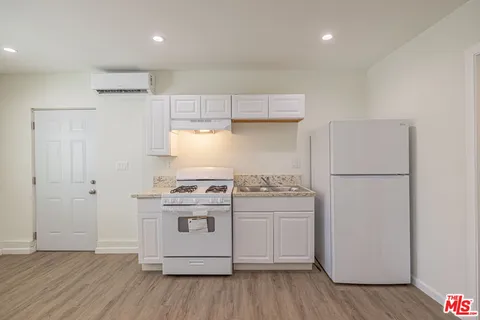a kitchen with a stove a refrigerator and a hard wood floor