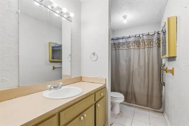 a bathroom with a granite countertop sink toilet a mirror a vanity and shower