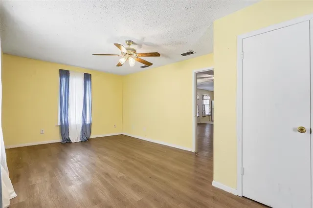 an empty room with wooden floor and a ceiling fan