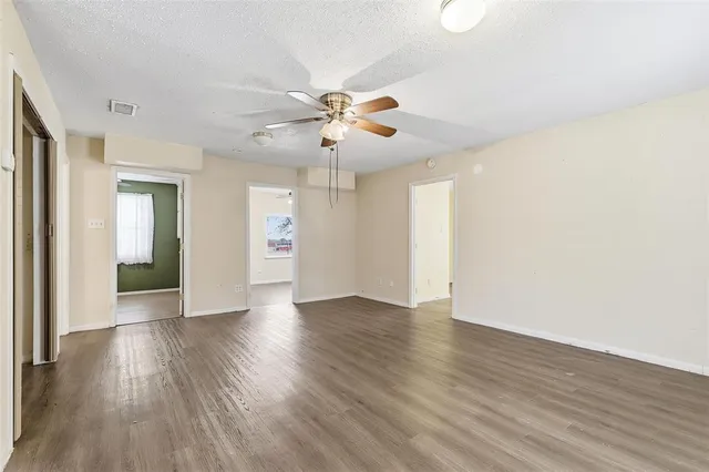 a view of an empty room with window and wooden floor