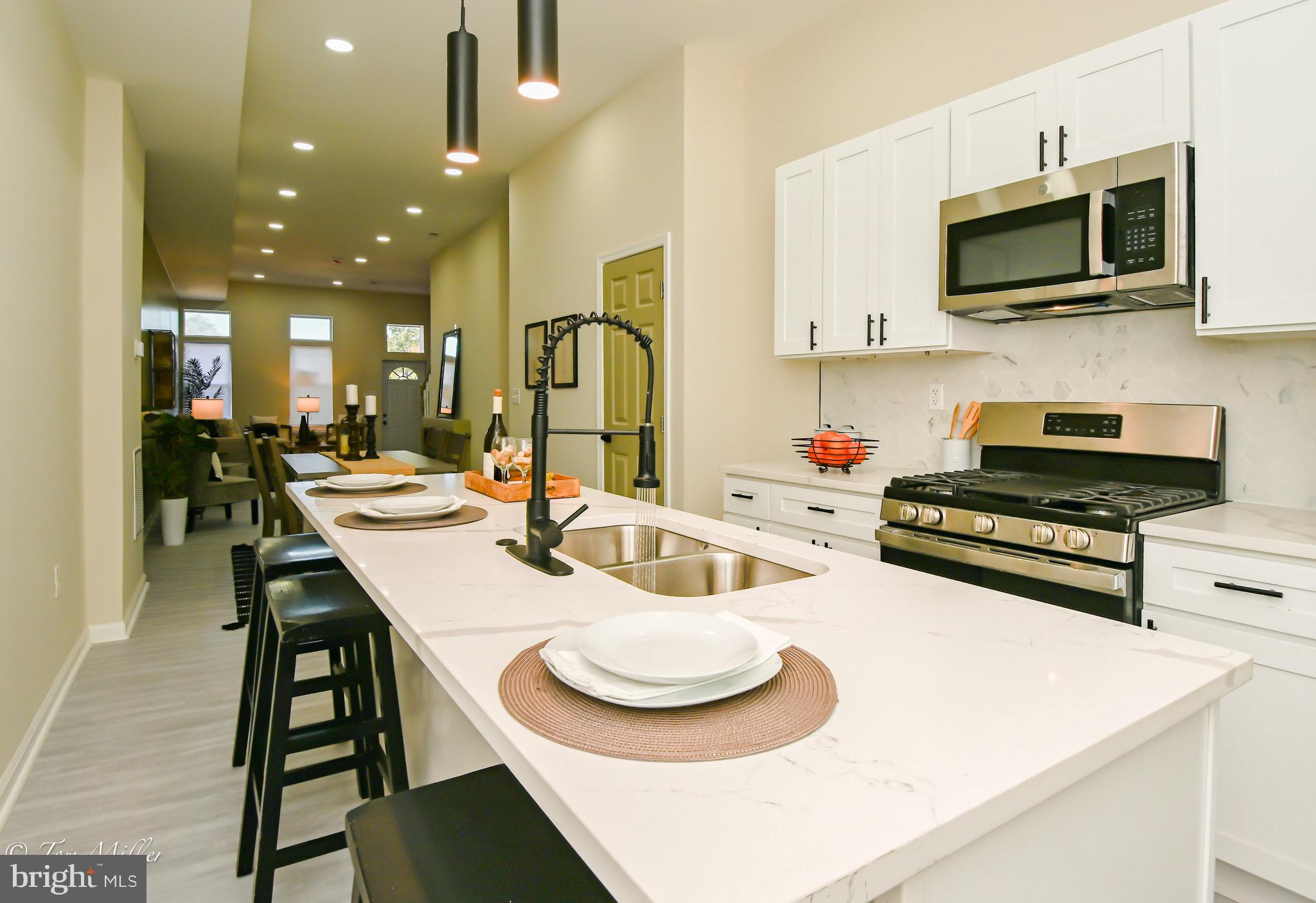 a kitchen with stainless steel appliances kitchen island granite countertop a sink and a white cabinets