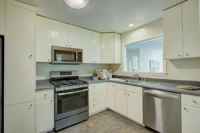 a kitchen with granite countertop white cabinets and white appliances
