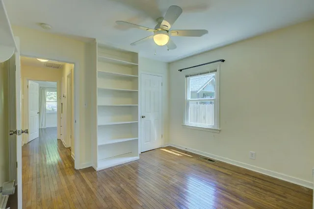 a view of an empty room with a window and wooden floor