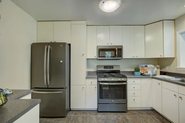 a kitchen with stainless steel appliances white cabinets and a refrigerator