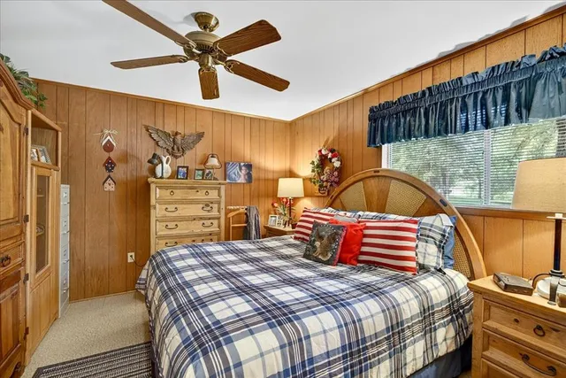 a bedroom with a bed a dresser and a chandelier