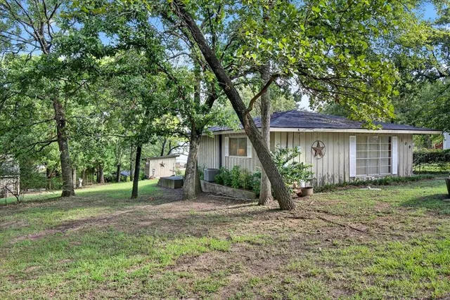 a front view of a house with garden and trees