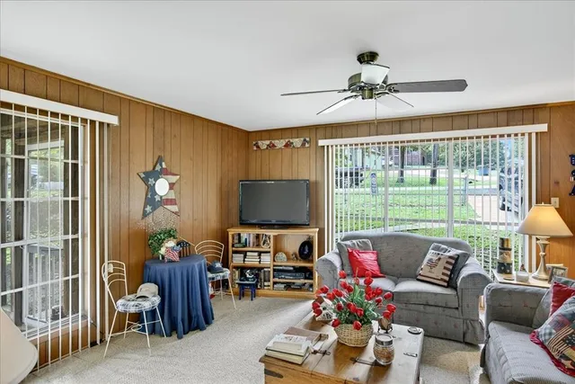 a living room with furniture a flat screen tv and a floor to ceiling window