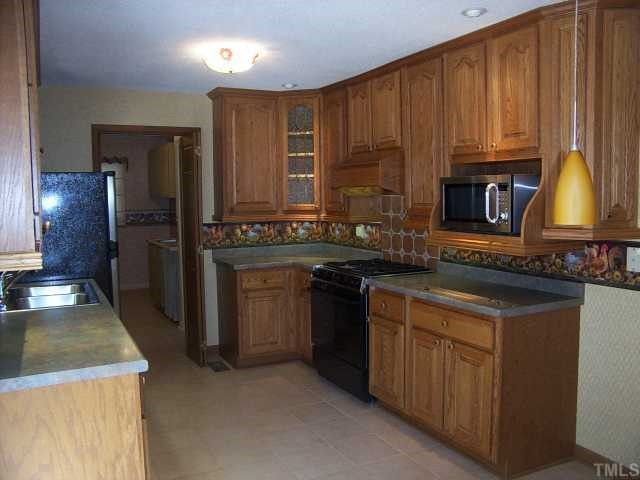 201 Cooper Branch Road Clayton, NC 27520 - Photo 9 of 12 Custom cabinets with accent lighting, ceramic tile floor and comes with SS and black appliances.
