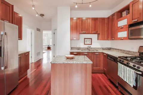 a kitchen with stainless steel appliances granite countertop a refrigerator a sink dishwasher a stove and white countertops with wooden floor