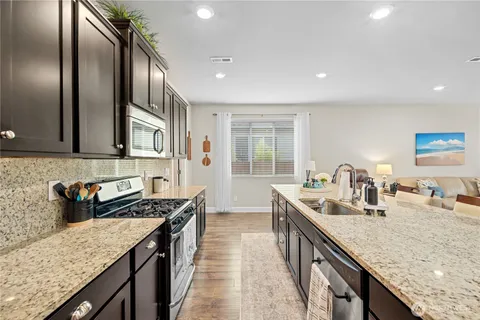 a kitchen with stainless steel appliances granite countertop a sink a stove and a wooden cabinets
