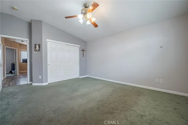 an empty room with closet and a chandelier fan