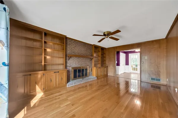 a view of a living room with wooden floor and a fireplace