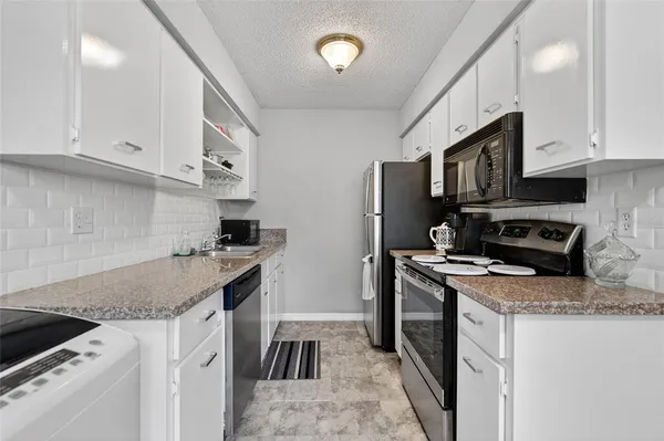 a kitchen with granite countertop a sink stove and refrigerator